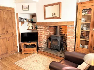 a living room with a brick fireplace and a television at Cosy cottage with views over the Shropshire hills - Pass the Keys in Ludlow