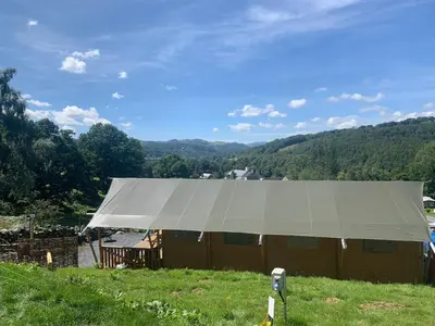 a large white tent in a field with a view at Mountain View Safari Tent with Hot Tub in The Heart of Snowdonia in Dolgellau