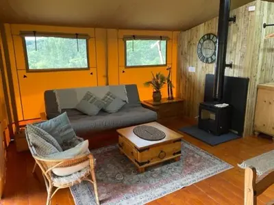a living room with a couch and a stove at Mountain View Safari Tent with Hot Tub in The Heart of Snowdonia in Dolgellau