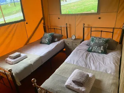 two beds in a room with two windows at Mountain View Safari Tent with Hot Tub in The Heart of Snowdonia in Dolgellau