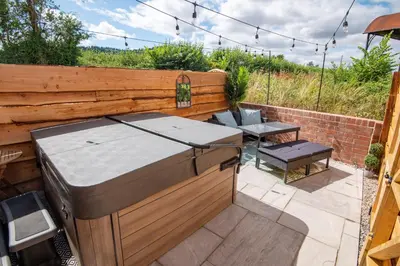 a barbecue grill in a backyard with a table at Apple Tree Cottage - Cosy 2 Bed with Deluxe HOT TUB & Log Burner in Hereford