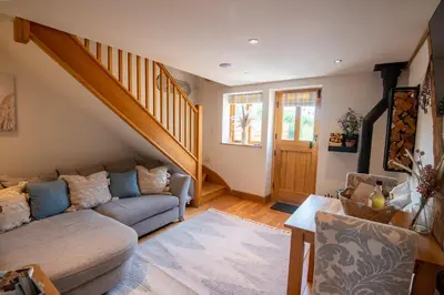 a living room with a couch and a staircase at Apple Tree Cottage - Cosy 2 Bed with Deluxe HOT TUB & Log Burner in Hereford