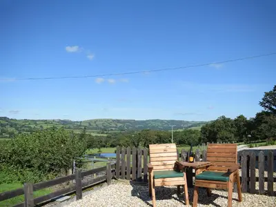 two wooden chairs and a table with a view at Dairy Cottage in Talley