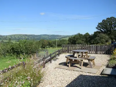 a picnic table in a garden with a fence at Dairy Cottage in Talley