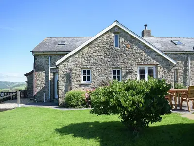 a stone house with a picnic table in front of it at Barn Cottage in Talley