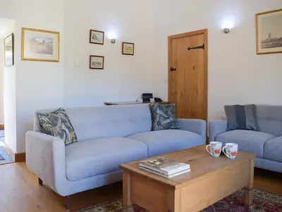 a living room with a blue couch and a coffee table at Barn Cottage in Talley