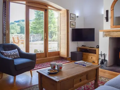 a living room with a couch and a table and a tv at Barn Cottage in Talley