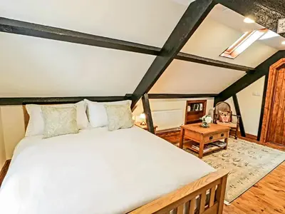 a bedroom with a large bed and a table at Yr Hen Beudy in Tywyn