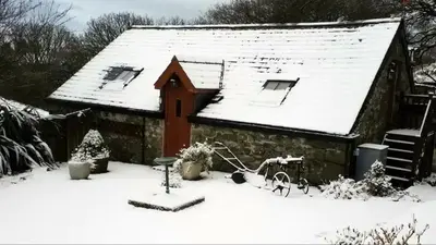 a small house with snow on the roof at Yr Hen Beudy in Tywyn