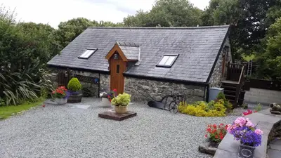 a small house with flowers in front of it at Yr Hen Beudy in Tywyn