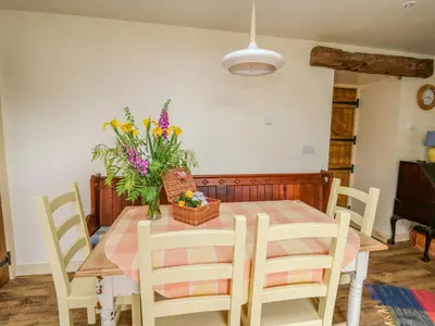 a dining room table with a vase of flowers on it at Buzzards Breg in Builth Wells