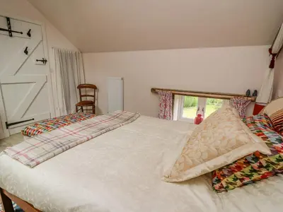 a bedroom with a white bed and a window at Buzzards Breg in Builth Wells