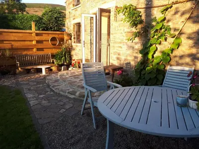 a patio with a table and two chairs and a bench at Buzzards Breg in Builth Wells