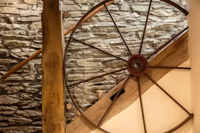 a wooden wheel in front of a stone wall at Hay Barn, Penrheol Farm, Unique Barn Conversion in Builth Wells