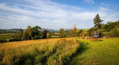 a grassy field with a picnic table in the distance at Hay Barn, Penrheol Farm, Unique Barn Conversion in Builth Wells