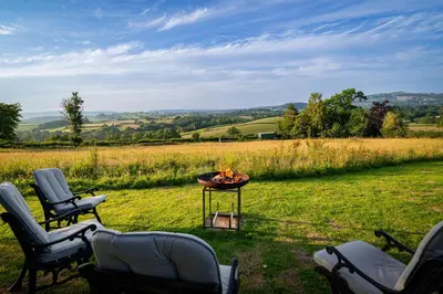 two chairs and a fire pit in a field at Hay Barn, Penrheol Farm, Unique Barn Conversion in Builth Wells