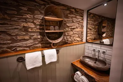 a stone bathroom with a sink and a mirror at Hay Barn, Penrheol Farm, Unique Barn Conversion in Builth Wells