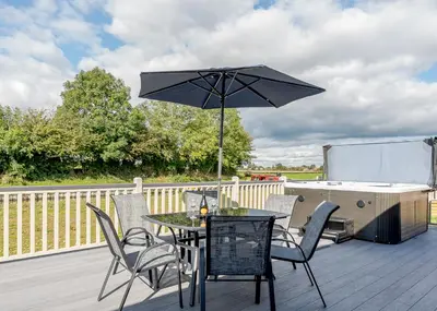 a table and chairs with an umbrella on a deck at Winston Farm Lodges in Ternhill
