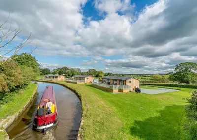 a boat on a river with houses in the background at Winston Farm Lodges in Ternhill