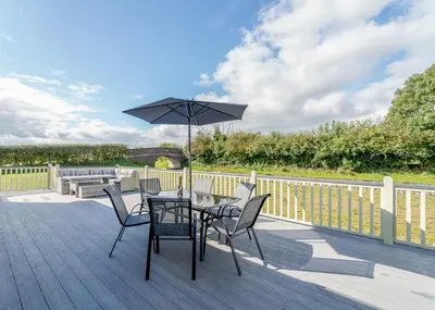 a table and chairs with an umbrella on a deck at Winston Farm Lodges in Ternhill