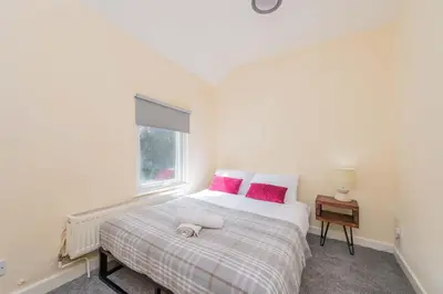 a bedroom with a bed with pink pillows and a window at Coton Hill Shrewsbury Cottage in Shrewsbury
