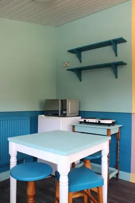a kitchen with a white table and two blue chairs at Poplar Lodge, Dee Valley Stays - cosy microlodge with detached private shower & WC in Corwen