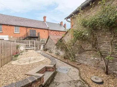 a backyard with a brick building and a stone wall at Stable Cottage, Bishops Castle in Bishops Castle