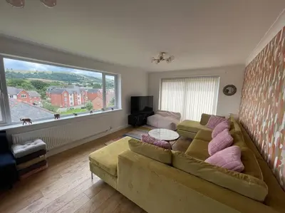 a living room with a couch and a large window at Luxury 4-5 Bed Home with Games Room and Balcony in Newtown
