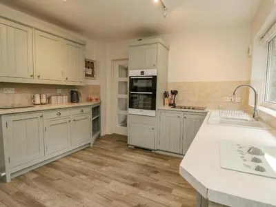 a large kitchen with white cabinets and a sink at Lleifior in Dolgellau