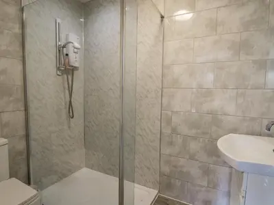 a shower with a glass door next to a sink at Lleifior in Dolgellau