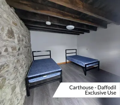two beds in a room with a stone wall at Cwm Clyd - Carthouse in Rhayader
