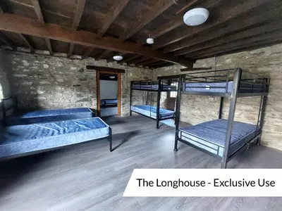 a room with three bunk beds in a stone wall at Cwm Clyd Longhouse in Llanwrthwl