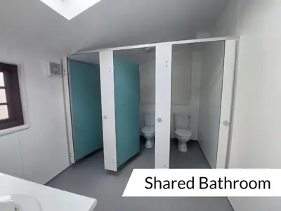 a bathroom with two toilets and a mirror at Cwm Clyd Longhouse in Llanwrthwl