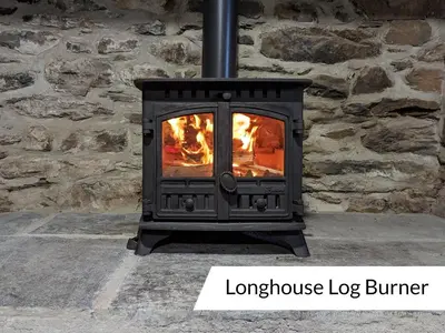 a stove with a fire in a stone wall at Cwm Clyd Longhouse in Llanwrthwl