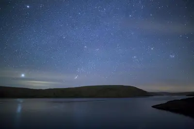 a starry sky over a body of water at night at Cwm Clyd Longhouse in Llanwrthwl