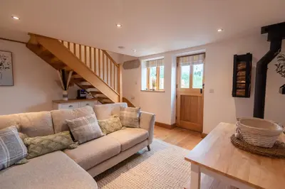 a living room with a couch and a staircase at Bramble Cottage - Cosy 2 Bed With Deluxe HOT TUB & Log Burner in Hereford