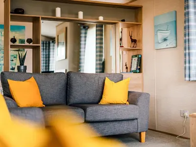 a gray couch with yellow pillows in a living room at Cledan in Aberaeron