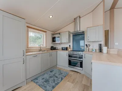 a kitchen with white cabinets and a blue rug at Cledan in Aberaeron