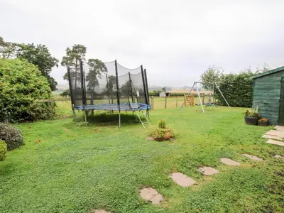 a playground with a trampoline in a yard at 6 Old Orchard in Much Wenlock