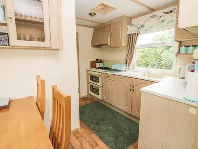 a kitchen with wooden cabinets and a table and a window at 8 Old Orchard in Much Wenlock