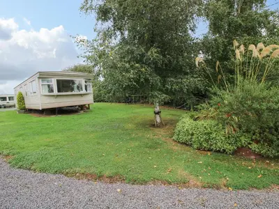a caravan in a yard with trees and grass at 8 Old Orchard in Much Wenlock