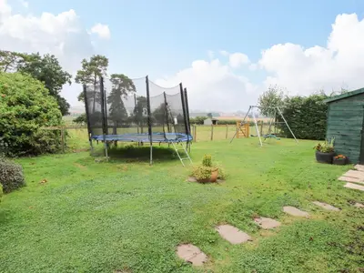 a playground with a trampoline in a yard at 4 Old Orchard in Much Wenlock