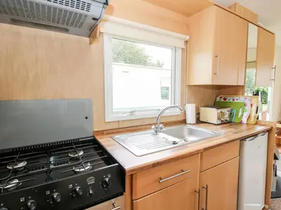a kitchen with a stove and a sink and a window at 3 Old Orchard in Much Wenlock