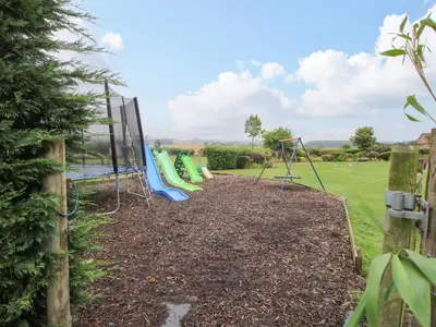 a playground in a garden with a fence at 2 Old Orchard in Much Wenlock