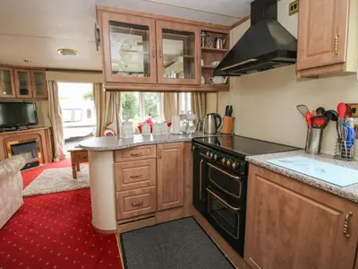 a kitchen with wooden cabinets and a black stove top oven at 2 Old Orchard in Much Wenlock