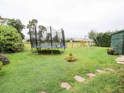 a yard with a trampoline in the grass at 9 Old Orchard in Much Wenlock