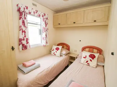 two beds in a small room with a window at 5 Old Orchard in Much Wenlock