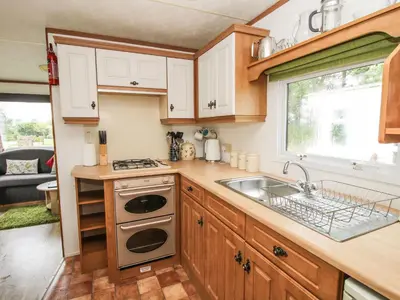 a kitchen with wooden cabinets and a sink and a window at 5 Old Orchard in Much Wenlock