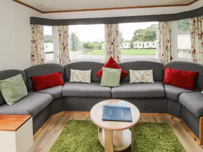 a living room with a couch with a book on it at 5 Old Orchard in Much Wenlock