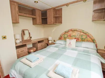 a bedroom with a large bed with wooden cabinets at 1 Old Orchard in Much Wenlock
